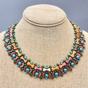 May include: A beaded necklace featuring a geometric design in shades of copper, green, and brown. The necklace is crafted with small, round beads and larger, rectangular beads.