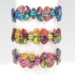 Peut inclure: Trois bracelets de perles orn&eacute;s de perles en verre iris&eacute; en forme de fleurs. Le bracelet du haut a des entretoises bleu sarcelle, celui du milieu des entretoises vert citron et celui du bas des entretoises magenta. Chaque bracelet est fait de petites perles m&eacute;talliques.