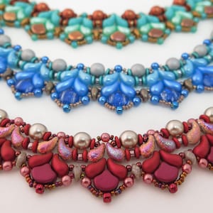 May include: Three layered beaded necklaces featuring intricate patterns of glass beads. The top necklace is teal and copper, the middle is blue and silver, and the bottom is deep red and metallic pink, all crafted with small seed beads and larger focal beads.