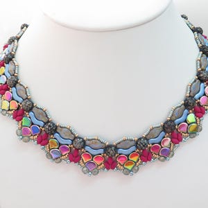 May include: A vibrant beaded necklace with a scalloped design. The necklace features iridescent, blue, pink, and grey beads, with accents of red and black. The necklace is displayed on a white mannequin.