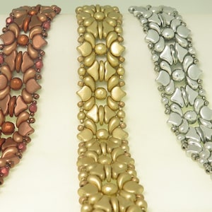 Könnte beinhalten: Drei Perlenarmbänder mit komplizierten Blumenmustern. Die Armbänder sind aus braunen, goldenen und silbernen Perlen gefertigt.