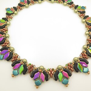 Könnte beinhalten: Eine mehrfarbige Perlenkette mit schwarzen, grünen, blauen und rosa Perlen. Die Kette besteht aus kleinen, runden Perlen und hat ein geometrisches Design.