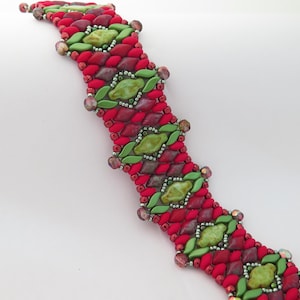 Puede incluir: Una pulsera de cuentas con un patrón repetitivo de cuentas rojas, verdes y moradas. La pulsera tiene forma curva y está hecha de cuentas de varios tamaños y formas. El cierre es de color bronce.
