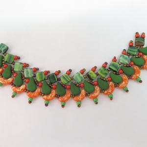 May include: A beaded necklace featuring a curved arrangement of green square beads, matte green teardrop beads, and orange crescent-shaped beads. The design is accented with small red and metallic seed beads, creating a vibrant, multi-textured pattern.
