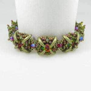 May include: A green, brown and multi-coloured beaded bracelet with a geometric design.