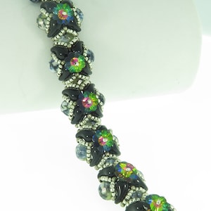 Puede incluir: Un brazalete de cuentas negras y plateadas con detalles de flores iridiscentes verdes, azules y rosas.