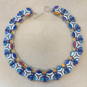 May include: A silver necklace featuring a geometric pattern of blue, white and orange beads. The necklace has a silver clasp.