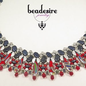 Könnte beinhalten: Eine Perlenkette mit geometrischem Design aus roten, silbernen und blauen Perlen. Die Kette ist aus verschiedenen Perlenformen und -größen gefertigt. Die Kette heißt "beadesire jewelry".