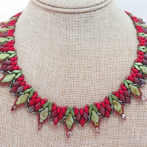 May include: A beaded necklace with a striking design. The necklace features a repeating pattern of red, burgundy, and green beads. The necklace is displayed on a neutral-colored surface, showcasing the intricate details and vibrant colors of the jewelry.