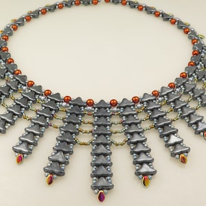 Può includere: Una collana di perline argentate e rame con un design geometrico. La collana presenta un motivo a cascata di perline triangolari, creando un look unico e accattivante.