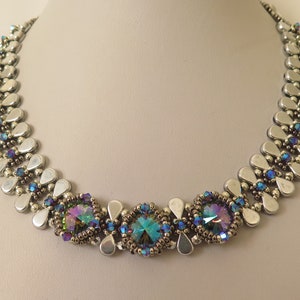 May include: A silver necklace featuring three iridescent blue and green crystal accents. The necklace is crafted with small silver beads and teardrop-shaped silver beads.