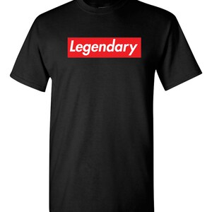 May include: Black t-shirt with the word "Legendary" in white text inside a red rectangular box on the front. The t-shirt has short sleeves and a crew neck.