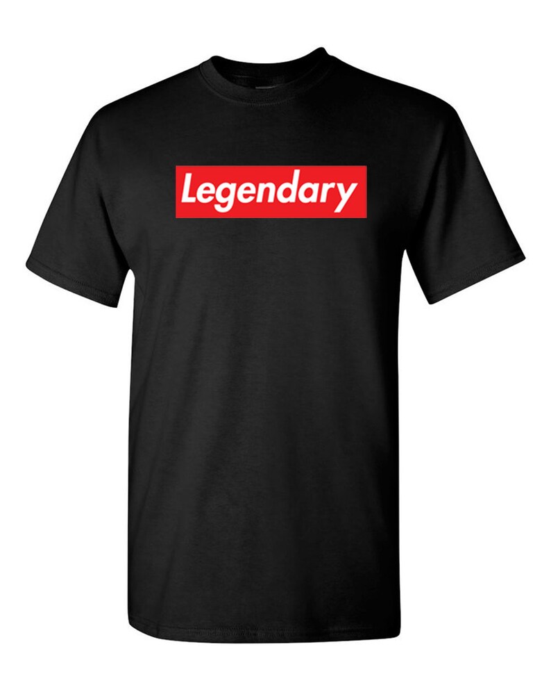 May include: Black t-shirt with the word "Legendary" in white text inside a red rectangular box on the front. The t-shirt has short sleeves and a crew neck.