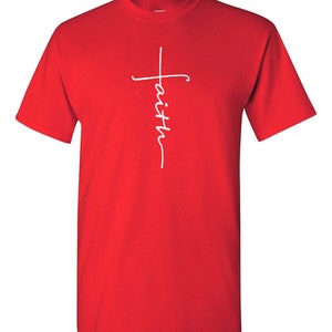 May include: A red t-shirt with a white cross design. The word "faith" is written vertically within the cross. The shirt is made of a soft material and has short sleeves.