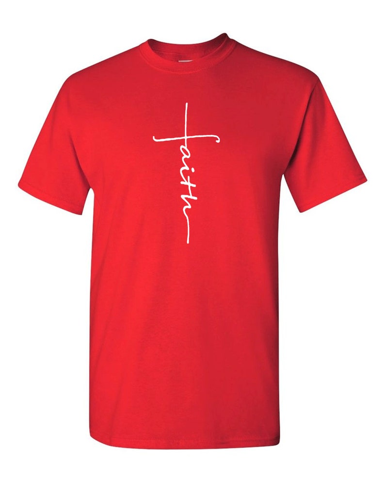 May include: A red t-shirt with a white cross design. The word "faith" is written vertically within the cross. The shirt is made of a soft material and has short sleeves.