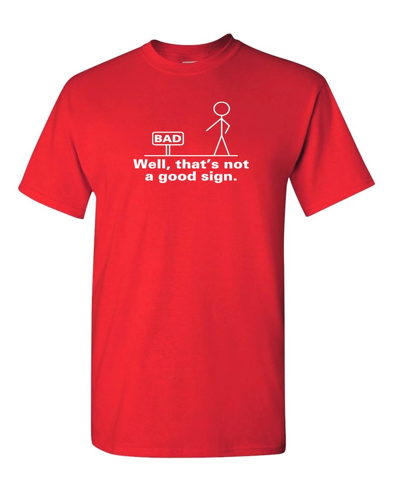 May include: Red t-shirt with a white stick figure standing in front of a sign that says "BAD". The text below the figure says "Well, that's not a good sign."