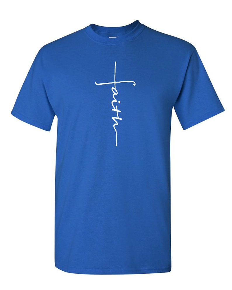 May include: Royal blue t-shirt with a white script design. The design features a cross with the word "faith" written vertically. The shirt has short sleeves and a crew neck.