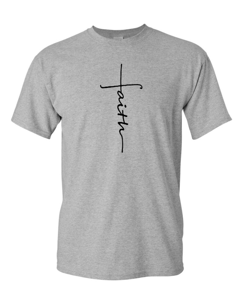 May include: A light gray t-shirt with a black cross design and the word "faith" written vertically. The shirt is made of a soft material and has short sleeves and a crew neck.
