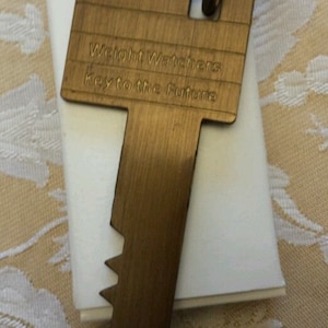 May include: A gold-coloured key-shaped keyring with the words "Weight Watchers Key to the Future" engraved on it.