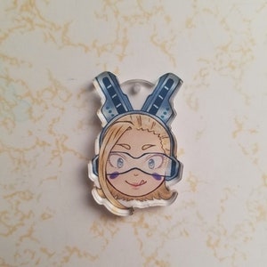 Puede incluir: Un llavero de un personaje de anime azul y blanco con cabello rubio y ojos azules. El personaje lleva un casco azul y blanco con visera.