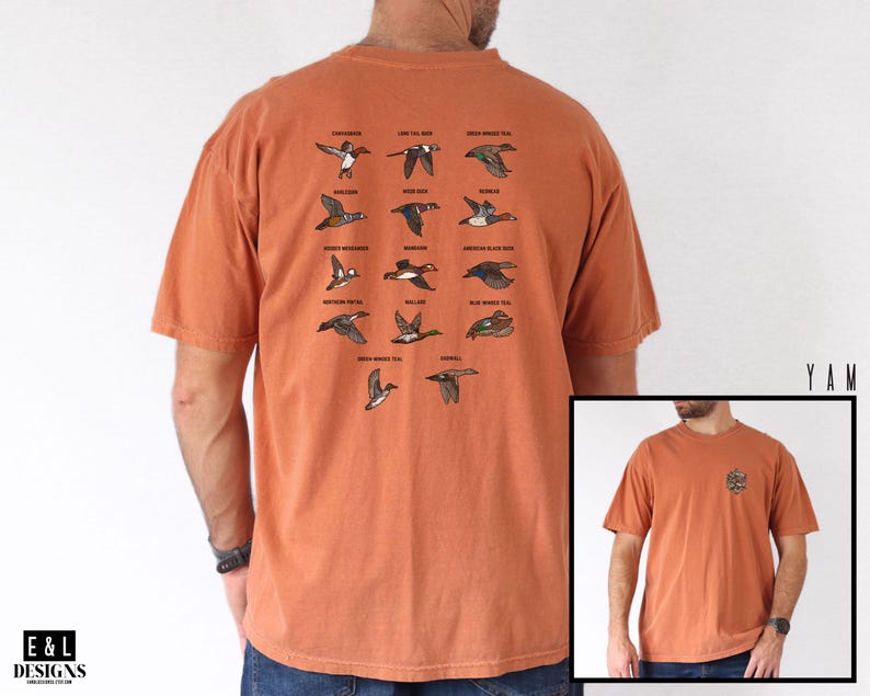 May include: Burnt orange t-shirt featuring illustrations of various duck species in flight, with their names above each image. The shirt also has a small graphic on the front. The brand logo "E & L DESIGNS" is visible on the bottom left.