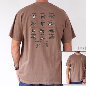 May include: Espresso-colored t-shirt featuring a collection of illustrated ducks in flight, each labeled with its species name. The shirt has a classic fit and short sleeves. The text "E & L DESIGNS" is in the lower left corner.