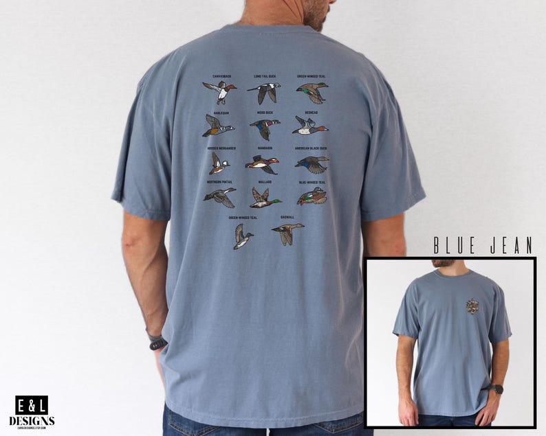 May include: Blue jean-colored t-shirt featuring a detailed illustration of various duck species in flight. The shirt has a classic crew neck and short sleeves. The text "BLUE JEAN" is printed on the bottom right corner of the image.