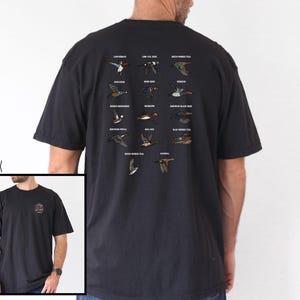 May include: Black t-shirt featuring a detailed illustration of various duck species in flight, with their names printed above. The shirt also has a small design on the front and the word "BLACK" printed on the left side.