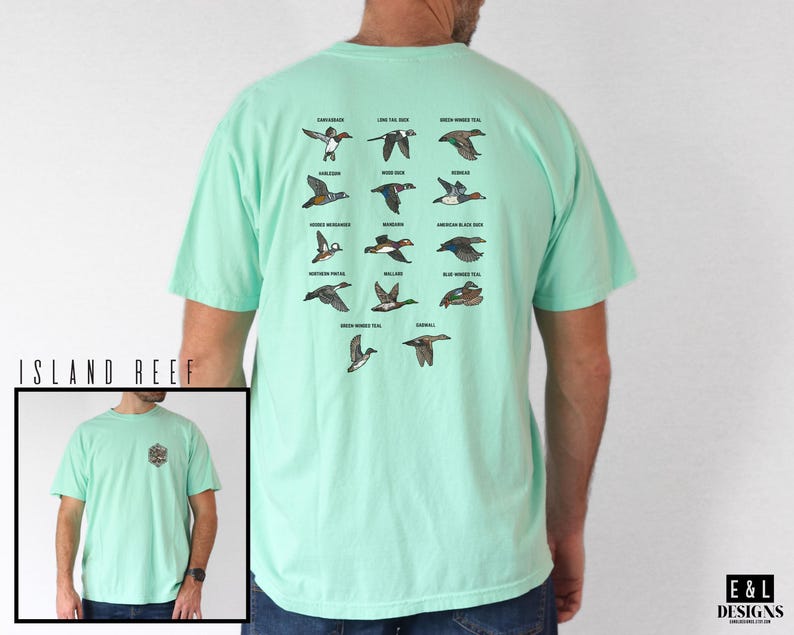 May include: A light green t-shirt featuring a detailed illustration of various duck species. The back of the shirt displays a grid of duck illustrations with their names. The shirt also has a small logo on the front. The brand name "E&L DESIGNS" is visible.