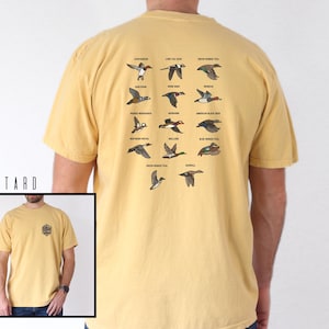 May include: Mustard-colored t-shirt featuring a detailed graphic of various duck species with their names. The shirt has a small graphic on the front and the text "E & L DESIGNS" on the bottom right.