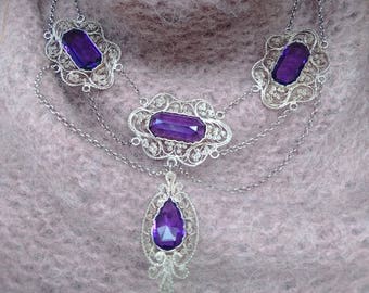 Fabulous filigree statement festoon with detailed lace-like silver settings holding gorgeous faceted amethys colored pastes. Great necklace!