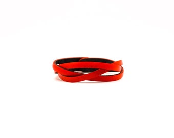 May include: A red leather bracelet with a braided design.