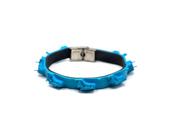 May include: A blue rubber dog collar with a metal buckle. The collar has a textured surface with small bumps.