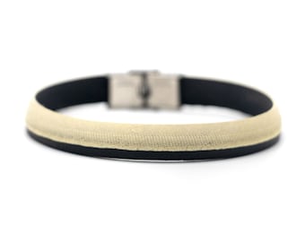 May include: A black and cream colored bracelet with a silver clasp.