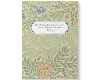 May include: A rectangular notebook featuring a light green background with a repeating pattern of sage green leaves, blue flowers, and pink blossoms. A central white label with a blue border displays the text: I love the Lord, because He hears my voice & my supplications. Psalm 116:1.