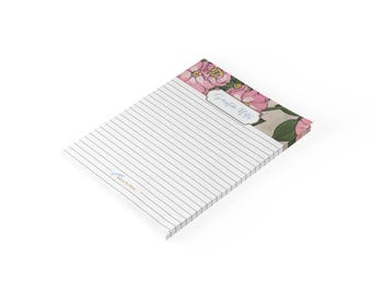 May include: A rectangular notepad with horizontal lines for writing. The top section features a floral pattern with pink flowers and green leaves. A white label with the text Scripture Notes is centred in the floral area. A small logo is at the bottom.