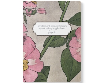 Può includere: Un taccuino rettangolare con sfondo grigio chiaro, fiori rosa e foglie verdi, caratterizzato da un'etichetta bianca centrale con il testo: I love the Lord, because He hears my voice & my supplications. Psalm 116:1.