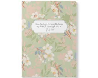 May include: A rectangular notebook with a sage green cover featuring a repeating pattern of white and pale pink flowers with green leaves. A central white label contains the text: I love the Lord, because He hears my voice & my supplications. Psalm 116:1.
