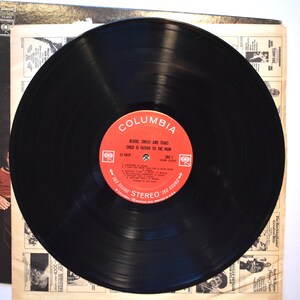 May include: A black vinyl record with a red label that says "Columbia" and "Blood, Sweat and Tears Child is Father to the Man". The record is on a white background.