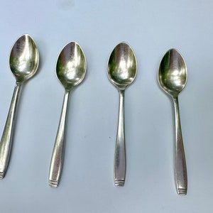 May include: Four silver teaspoons with rounded bowls and simple, elegant handles.