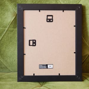 May include: Black picture frame with a brown cardboard backing. The frame has a matte finish and is ready to be used for a picture or artwork.