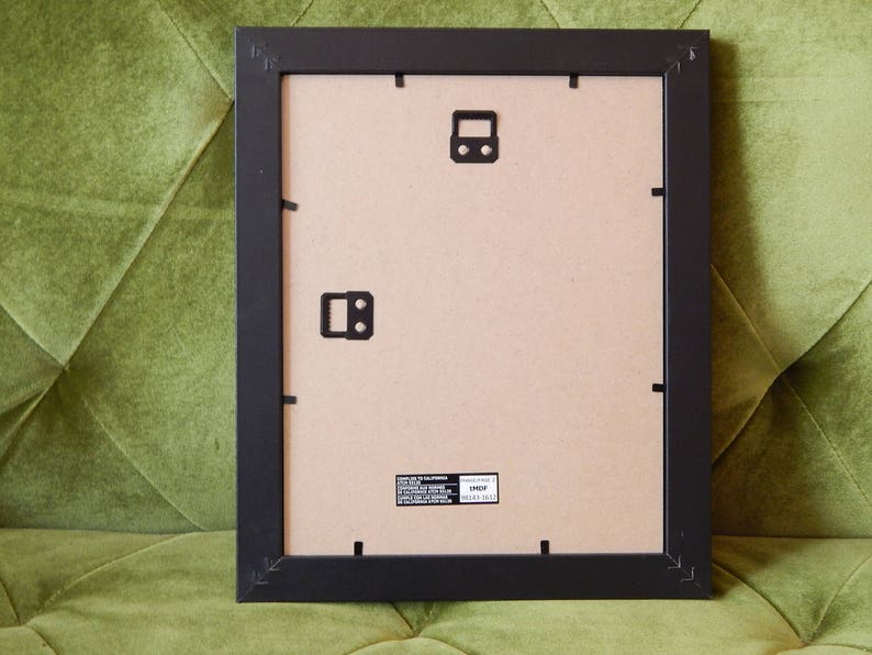 May include: Black picture frame with a brown cardboard backing. The frame has a matte finish and is ready to be used for a picture or artwork.