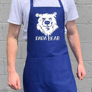 May include: A blue apron with a white bear graphic and the text "Papa Bear".