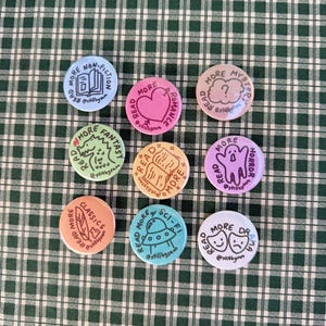 Puede incluir: Nueve botones redondos de colores con las palabras "More Non-Fiction", "More Romance", "More Mystery", "More Fantasy", "More Read", "More Horror", "More Classics", "More Sci-Fi" y "More Drama". Cada botón tiene un gráfico único.