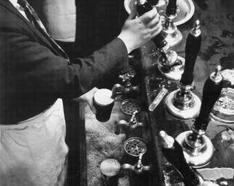 Bartender Pouring Stout in Dublin Pub – black and white photograph, by Marvin Koner, 1959