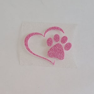 Op de afbeelding: Roze glitterhart met een roze glitterpootafdruk erin. Het hart is omrand met roze glitter.