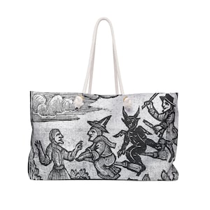May include: A large tote bag with a cream-colored rope handle. The bag features a black and white illustration of witches and a devil riding brooms. The background has a cloudy sky design.