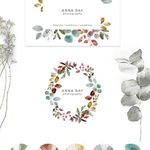 May include: A watercolor logo design featuring a wreath of leaves and berries in shades of green, brown, red, and blue. The text "ANNA RAY photography" is centered in the wreath. The logo is perfect for a photographer specializing in lifestyle, newborn, and wedding photography.