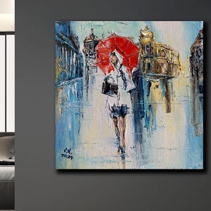 Könnte beinhalten: Ölgemälde einer Person, die mit einem roten Regenschirm durch eine Stadtstraße geht. Das Kunstwerk verwendet Blau-, Weiß- und Gelbtöne mit sichtbaren Pinselstrichen. Das Gemälde ist mit "J.N. 2024" signiert.