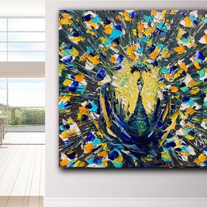 Könnte beinhalten: Ein quadratisches, strukturiertes Ölgemälde eines Pfaus. Das Kunstwerk zeigt eine lebendige Darstellung von Farben, darunter Gelb, Blau und Orange, mit einem dunklen Hintergrund. Die Form des Pfaus steht im Mittelpunkt, mit seinem aufgefächerten Schwanz und Körper in dicken Pinselstrichen.